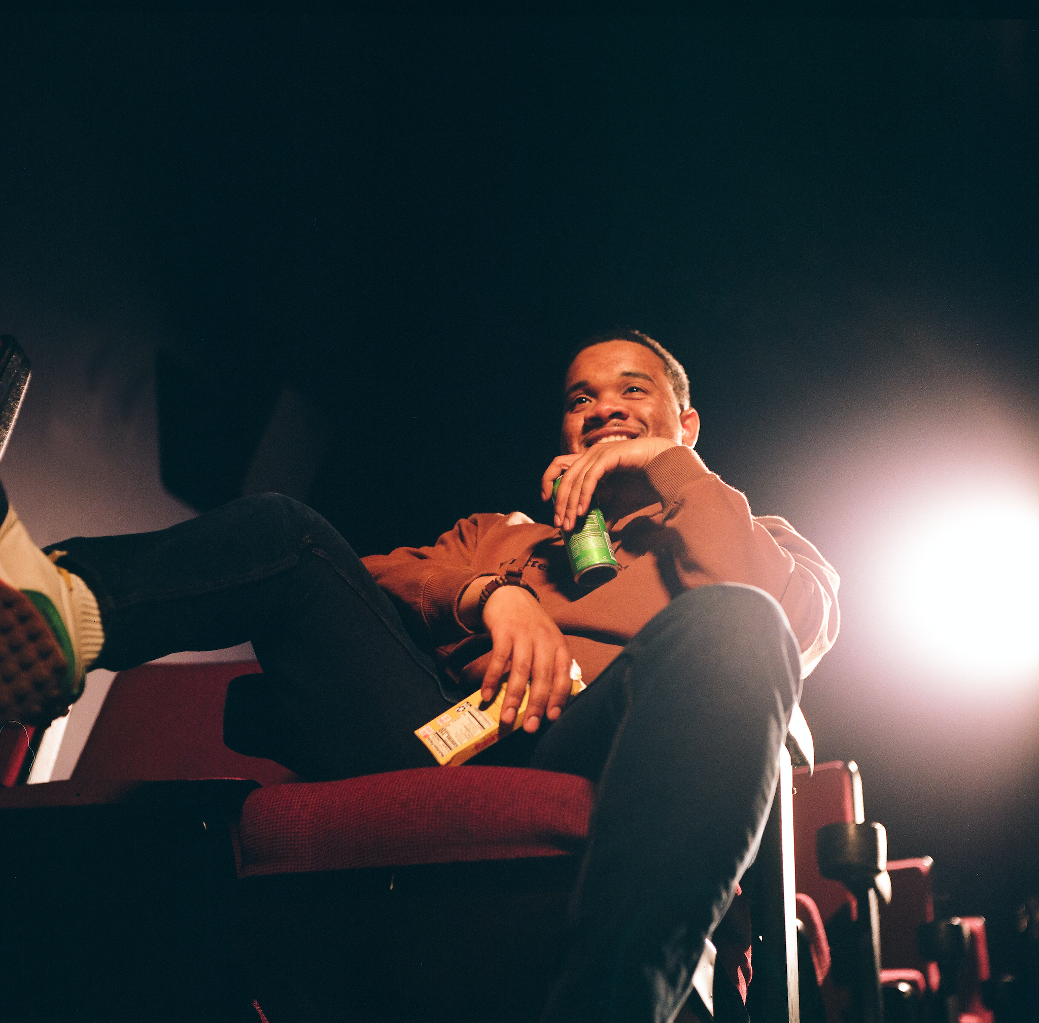 Sultan ali sits on movie theater chair smiling